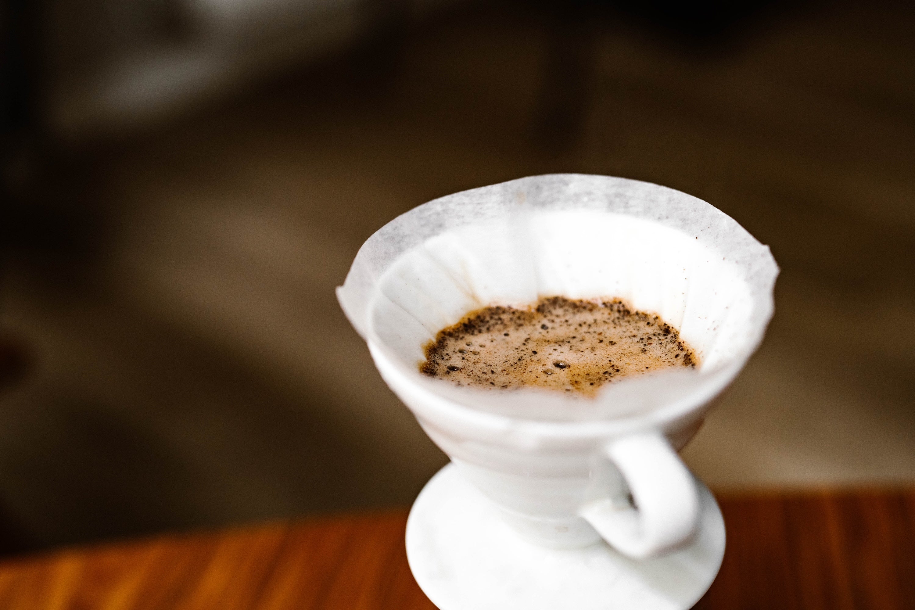 White coffee filter with coffee grounds on a wooden surface