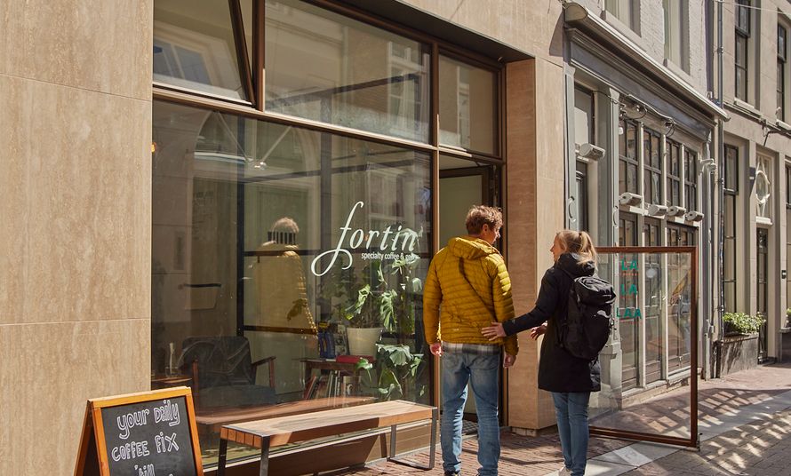 Two people standing outside Fortin Specialty Coffee Bar on a city street.