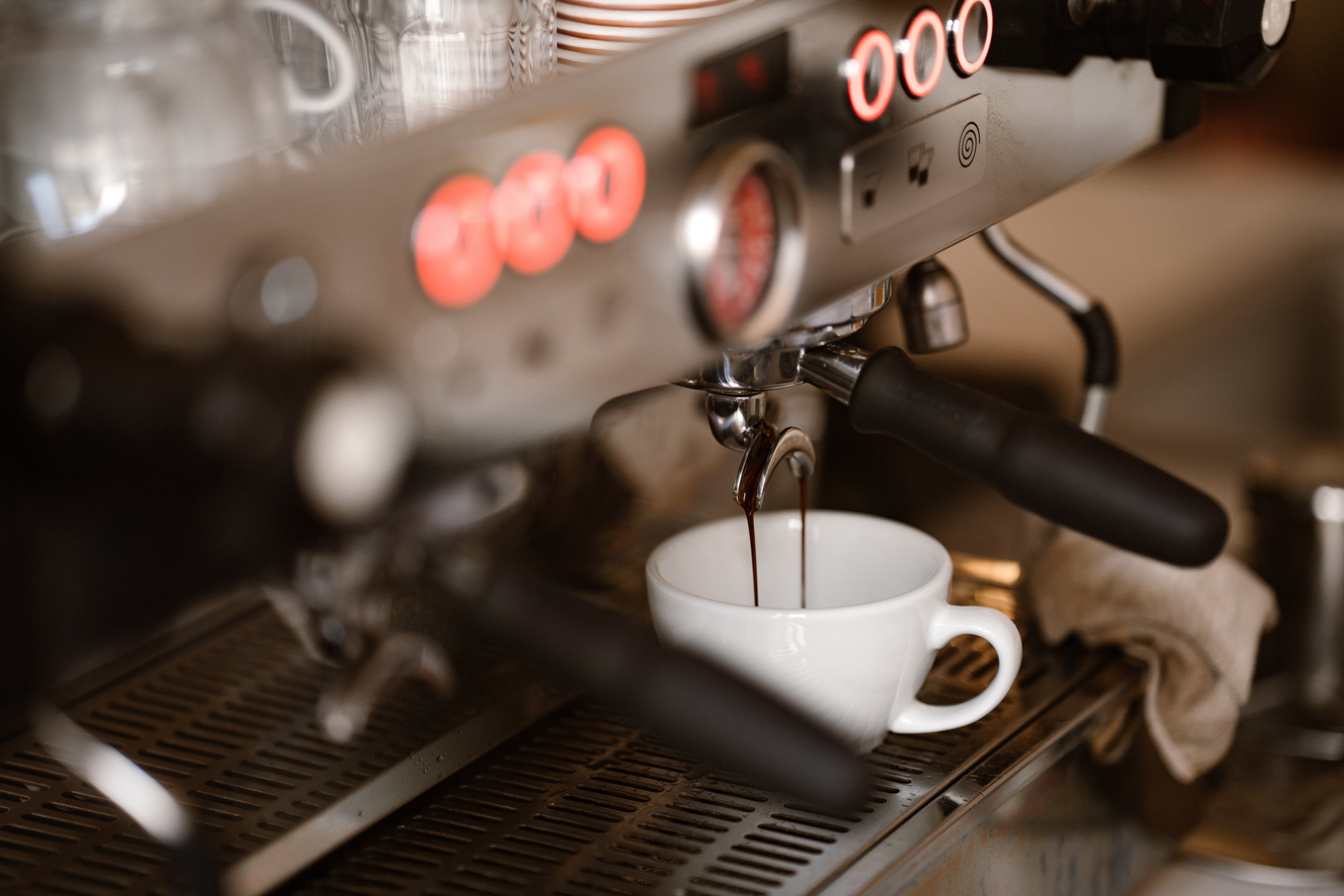 Espresso machine brewing a cup of coffee with visible steam and steam wand.