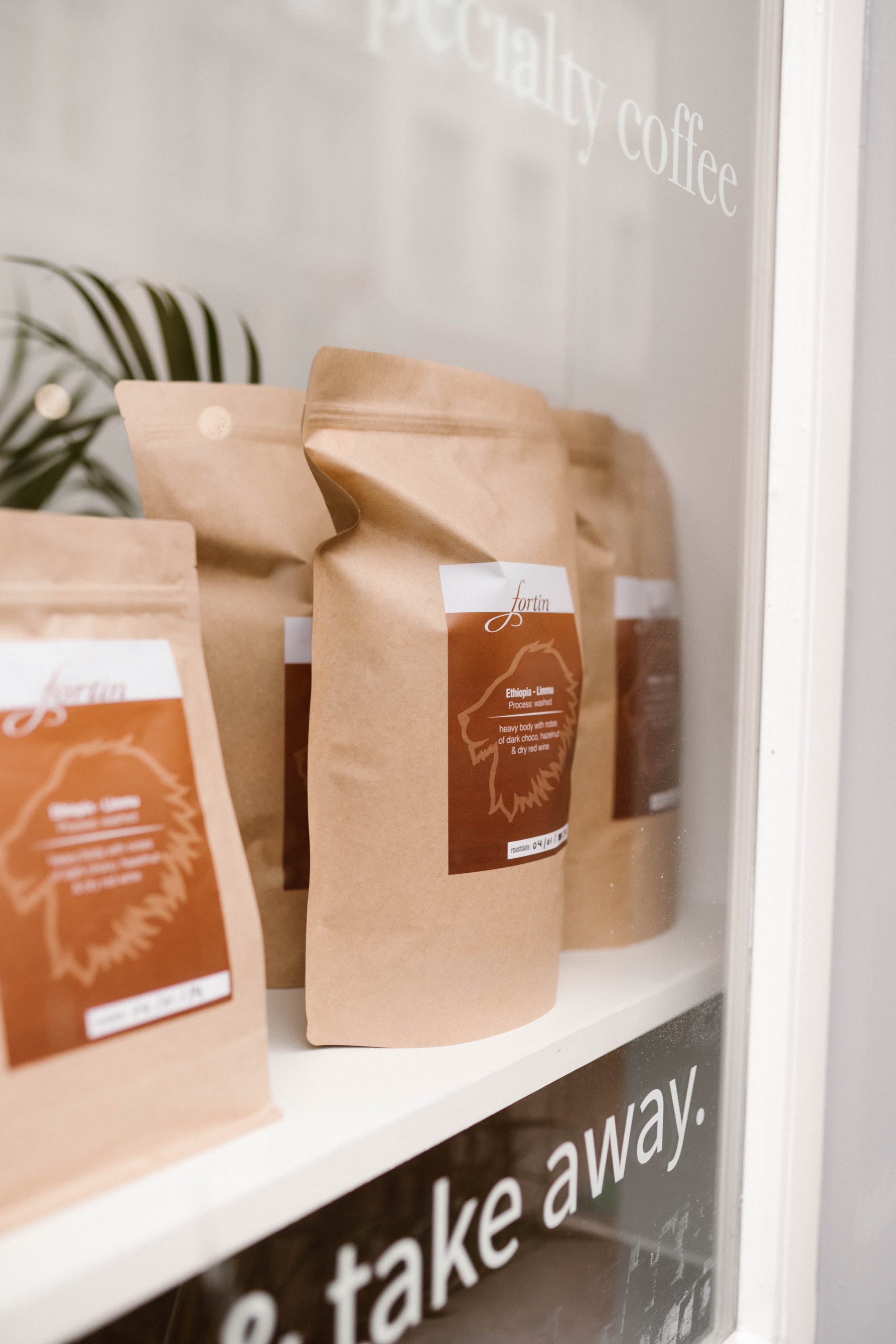 Kraft paper coffee bags on a shelf with 'take away' sign